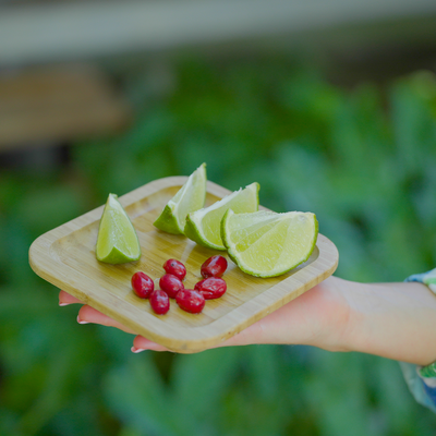 a person holding a tray of limes and cranberries
