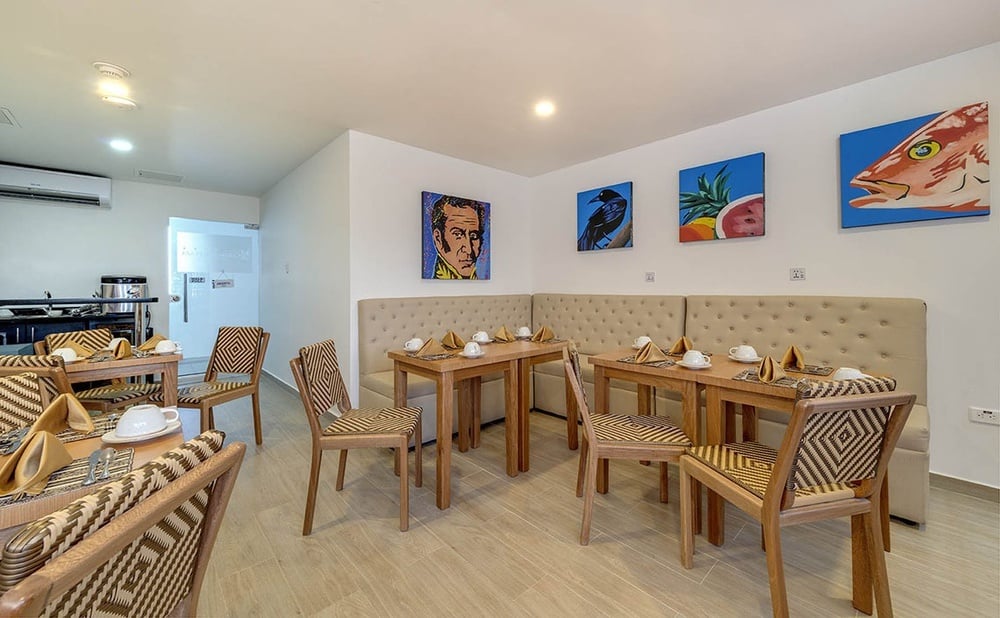 uma sala de jantar com mesas e cadeiras e pinturas na parede