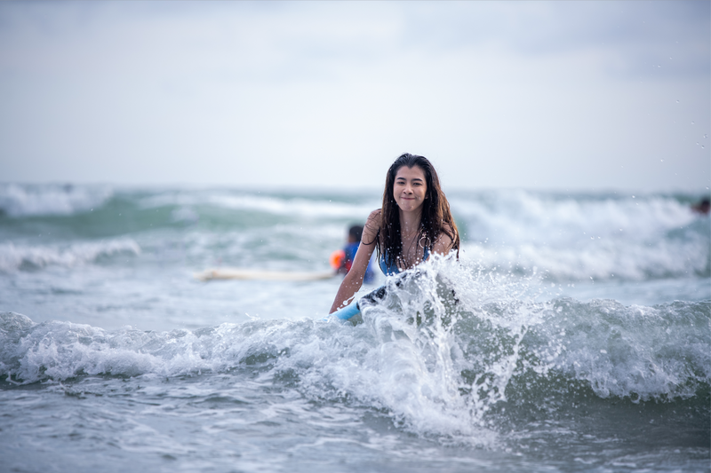 una mujer se sienta en una tabla de surf en el océano