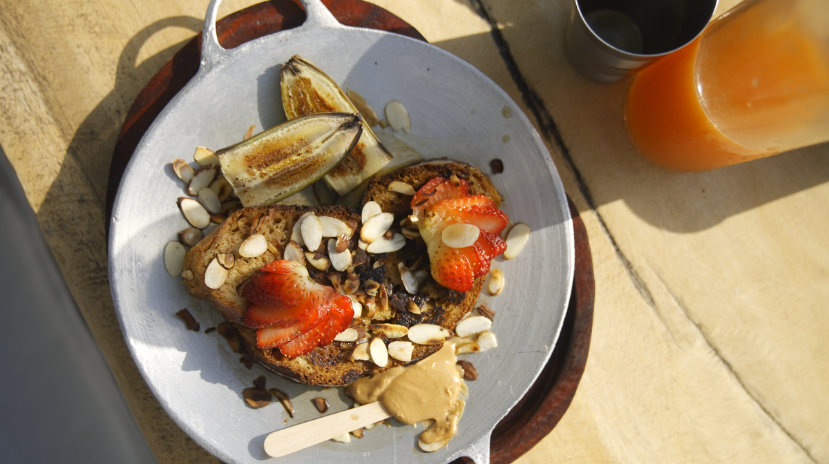 una mesa de madera se sienta en un patio de madera junto a un árbol