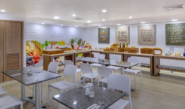 un restaurante lleno de mesas y sillas con una pizarra en la pared que dice 