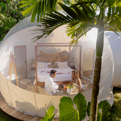 a man and a woman are sitting inside of a bubble tent