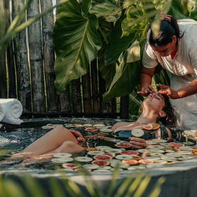 a woman is getting a massage in a bathtub filled with fruit slices