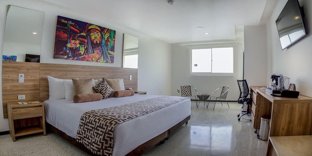 um quarto de hotel com uma cama king size e uma pintura de jimi hendrix