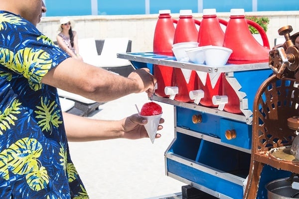 un hombre con una camisa azul y amarilla sostiene un cono de helado