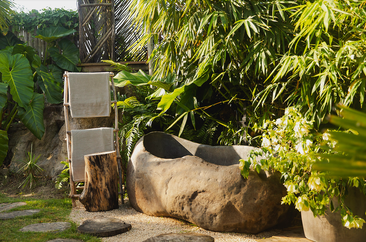 una bañera de piedra en un jardín rodeado de plantas
