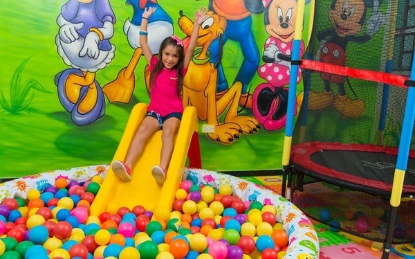 una niña se desliza por un tobogán en una piscina de pelotas
