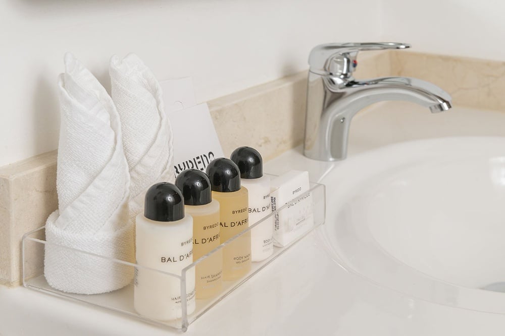 uma prateleira com garrafas de shampoo e condicionador ao lado de uma pia