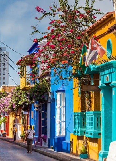 una mujer camina por una calle llena de edificios coloridos