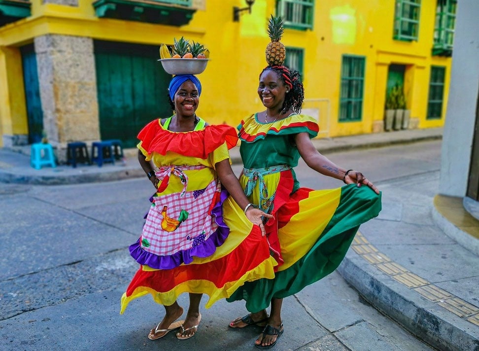 dos mujeres con vestidos coloridos y una piña en la cabeza