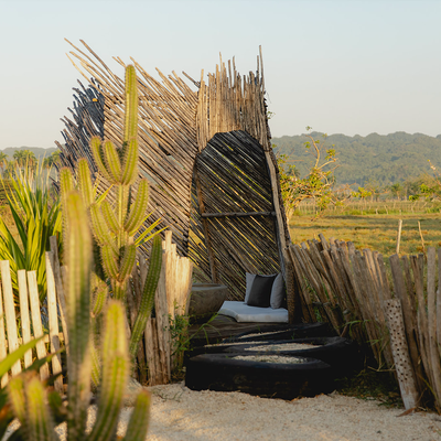 a chair made out of sticks is surrounded by a wooden fence