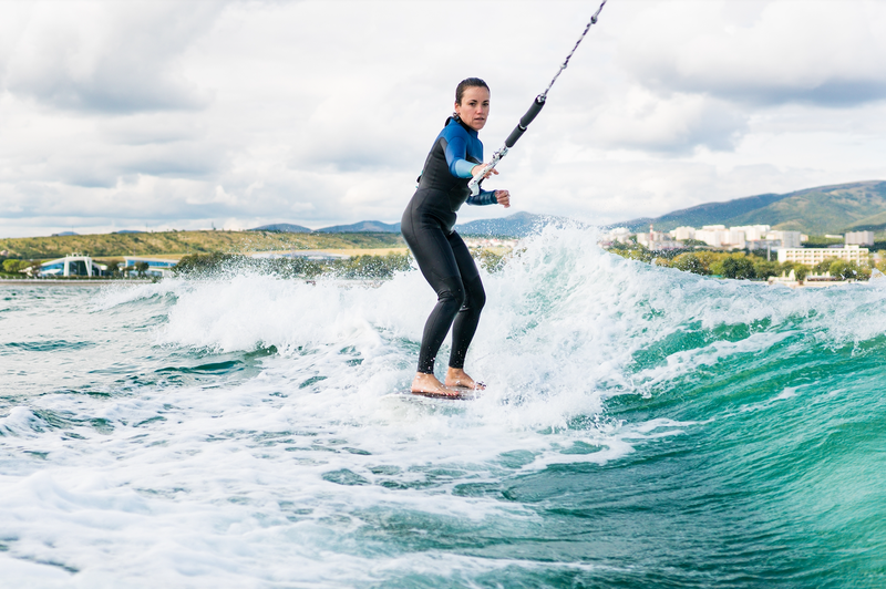 una mujer en traje de neopreno monta una tabla de surf en el océano