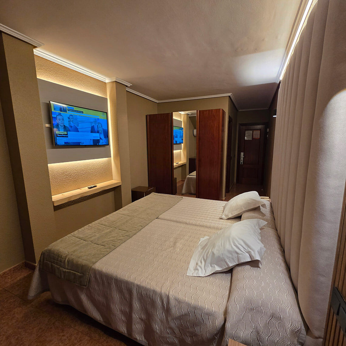 Two beds in a hotel room with a TV, closet, and door. TEST 4.