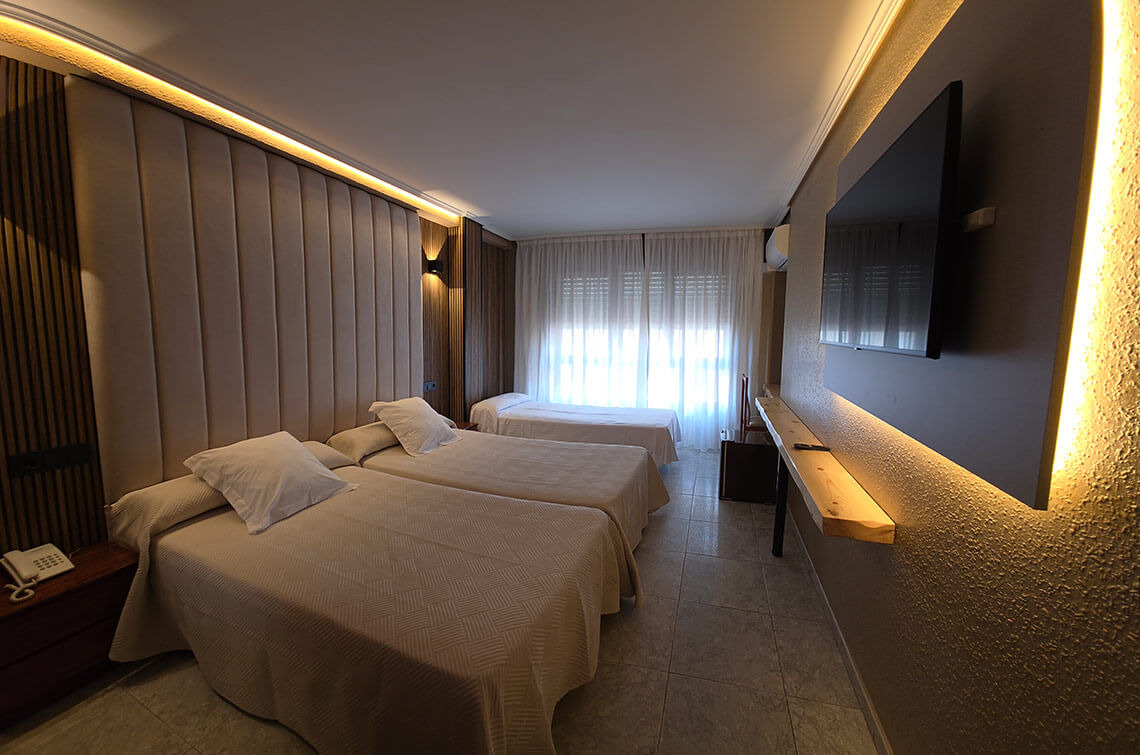 TEST 4 hotel room with three beds, large TV, and modern lighting.