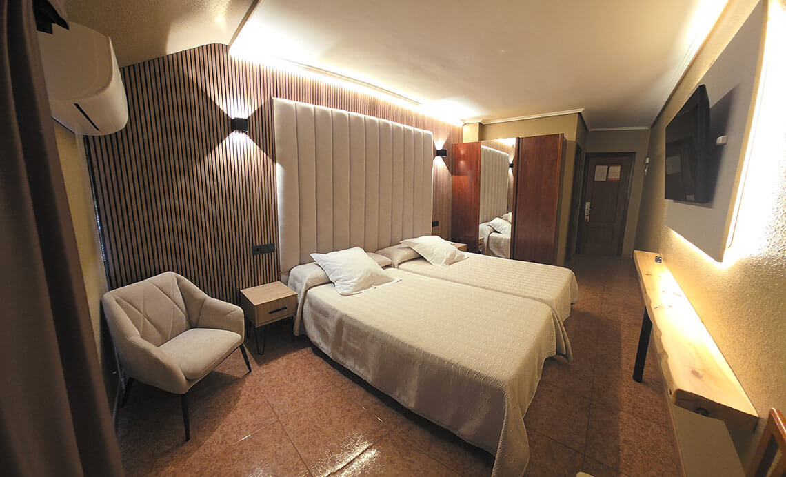 TEST 4 hotel room: two beds, armchair, modern decor, and TV.