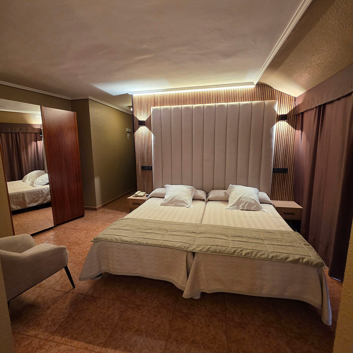 TEST 4 hotel room with two beds, large headboard, and cozy seating.