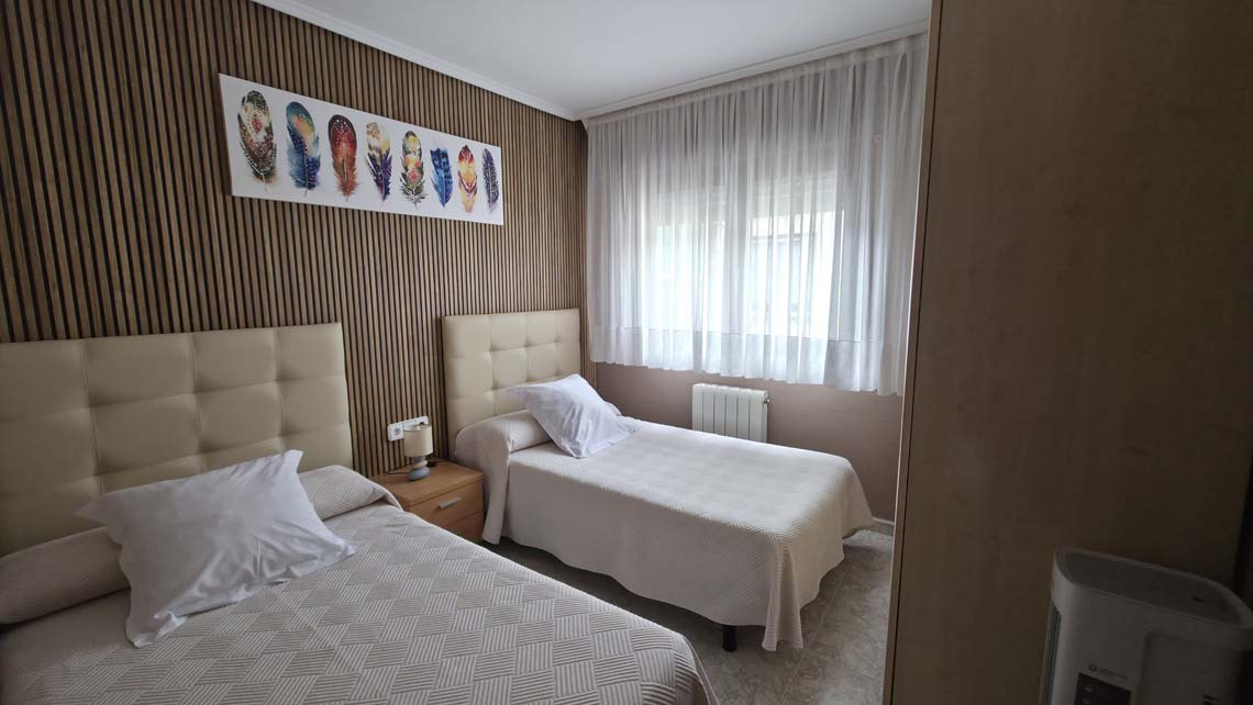 TEST 4: Twin beds with beige headboards in a hotel room with wood-paneled walls and feather art.