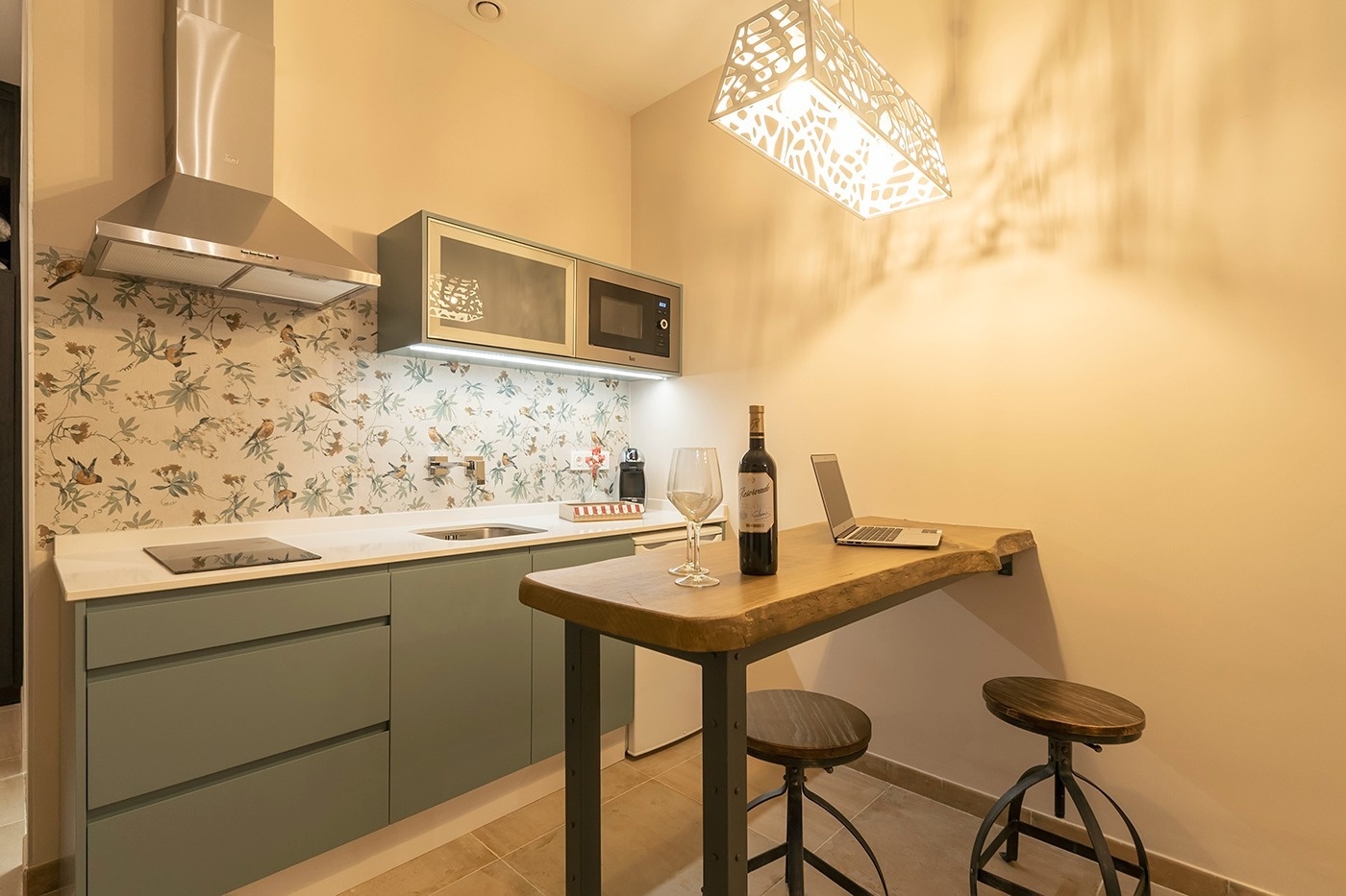 a bottle of wine sits on a table next to a laptop