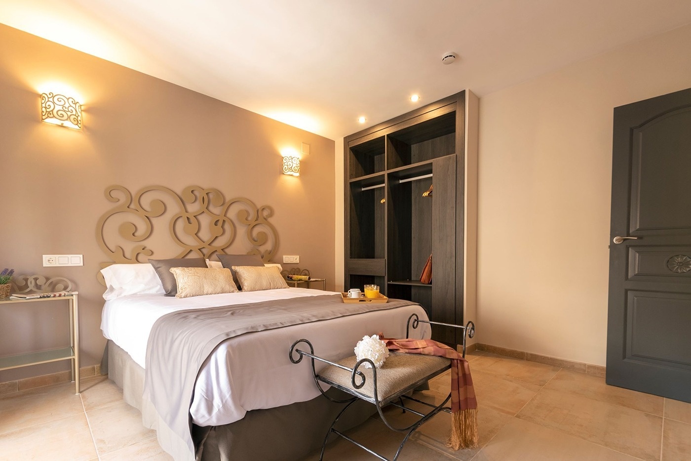 a bedroom with a large bed and a wrought iron bench