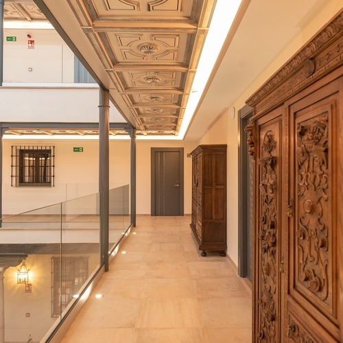 un pasillo con una puerta de madera tallada y una señal de emergencia en el techo