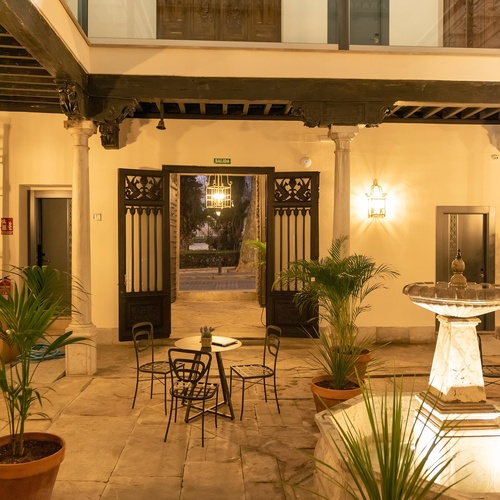 una piscina iluminada por la noche con un gran edificio en el fondo