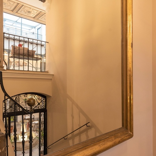 una escalera con una puerta de hierro forjado está reflejada en un espejo