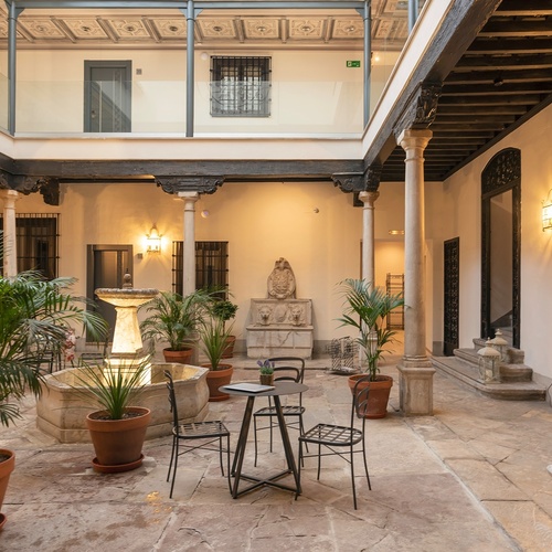 una mujer en un vestido rojo sostiene un cóctel junto a una piscina