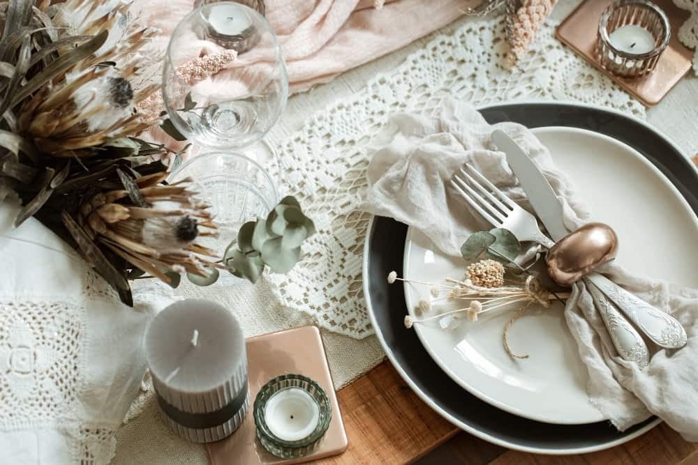 una mesa con platos cubiertos velas y flores secas