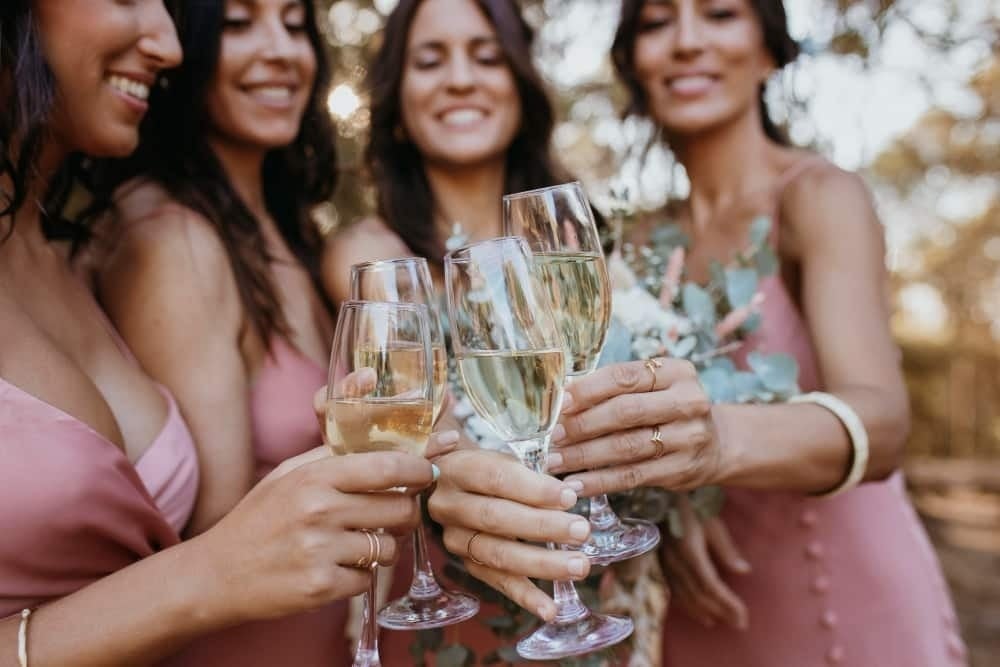 una novia y sus damas de honor brindan con copas de champán .