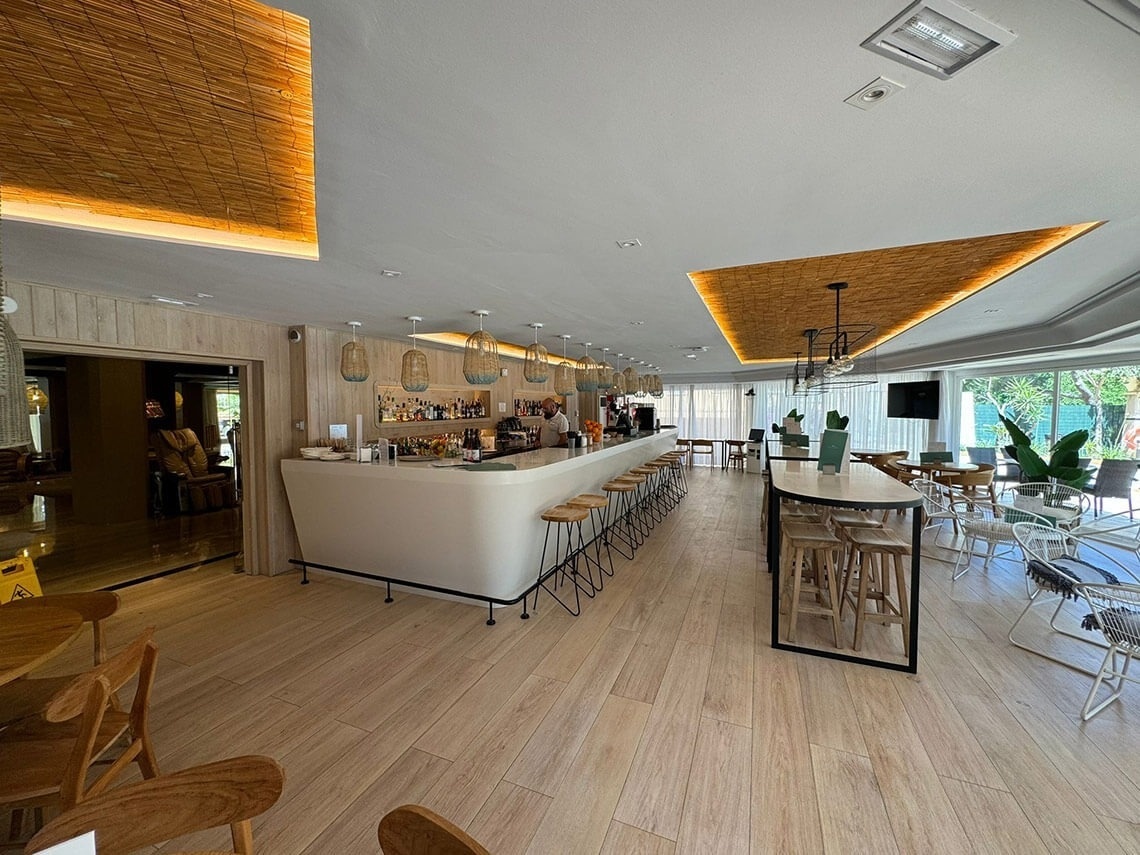 un restaurante lleno de mesas y sillas con un bar en el fondo .