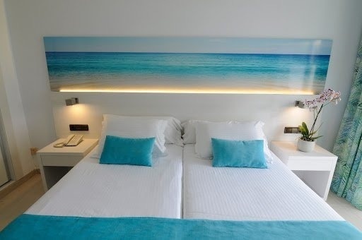 una habitación de hotel con dos camas y una pintura del océano en la pared .