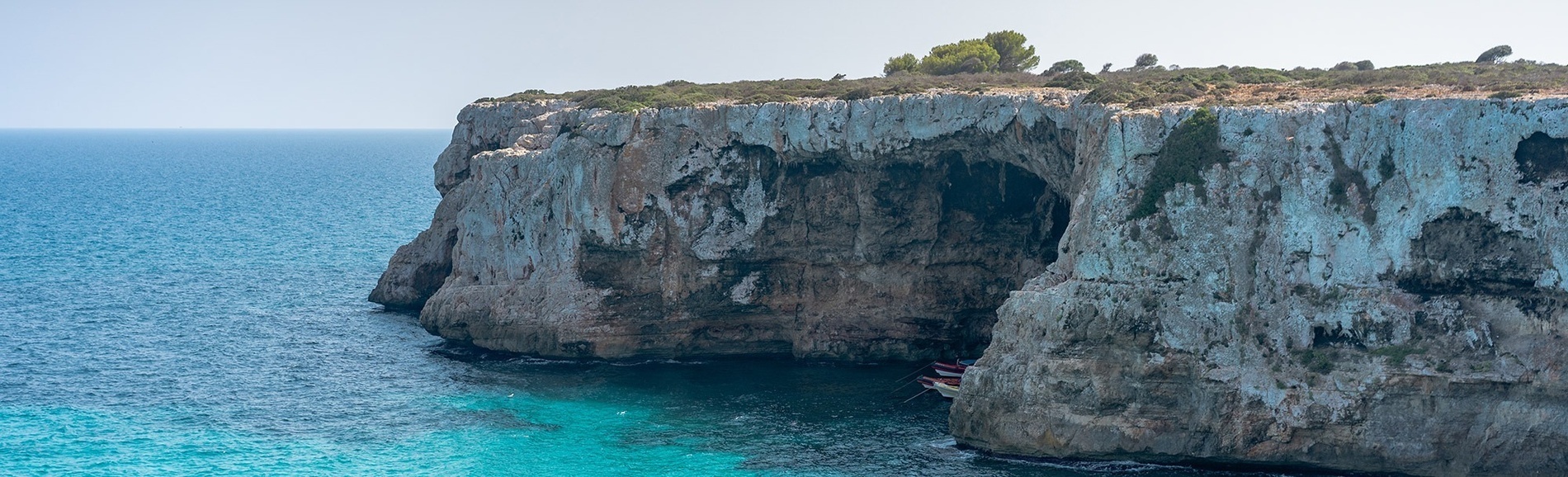a boat is sitting in the water near a cliff