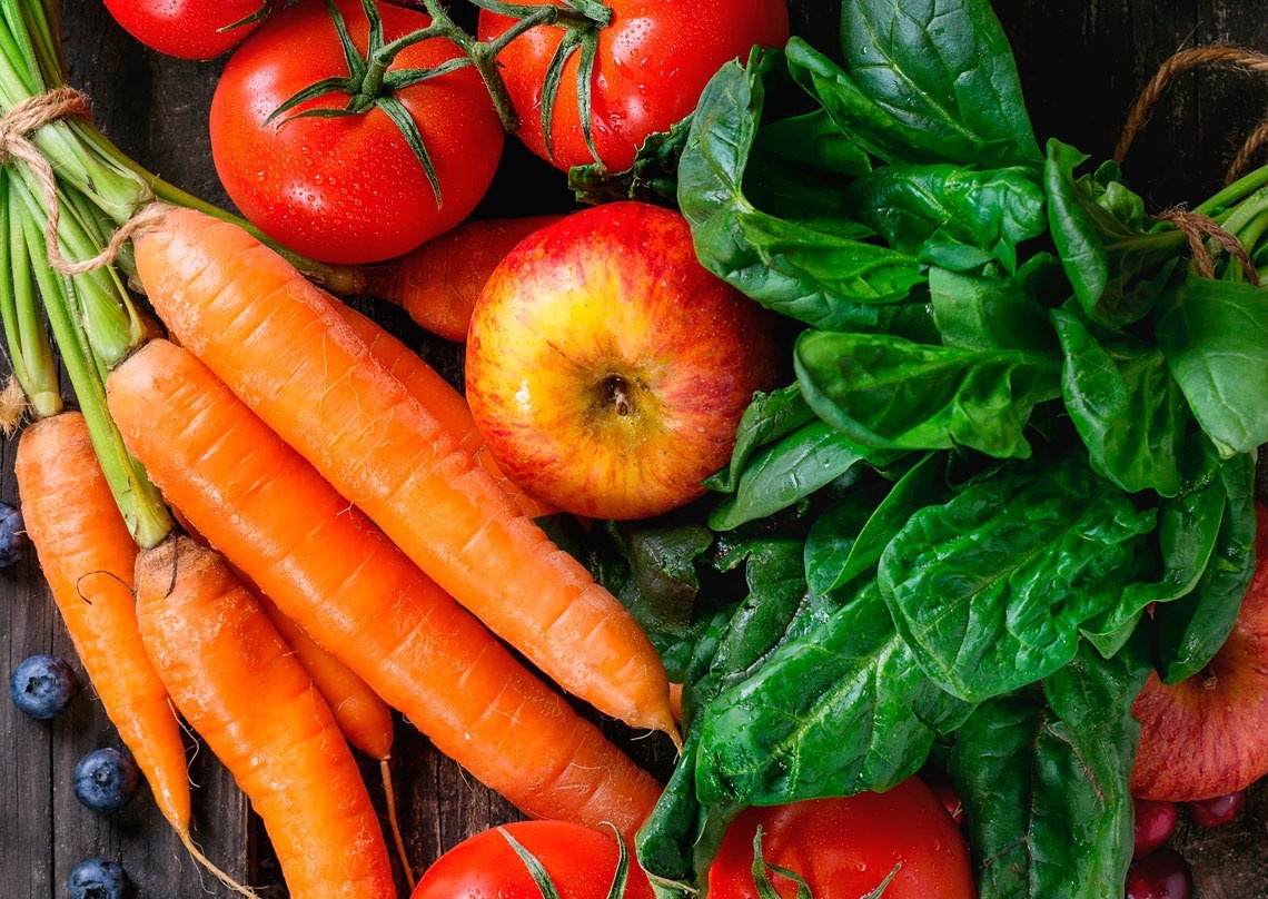 zanahorias , tomates , manzanas , espinacas y arándanos sobre una mesa de madera