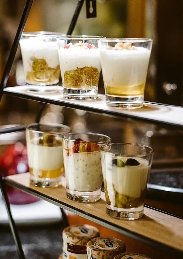a display of desserts on a shelf with jars of yogurt