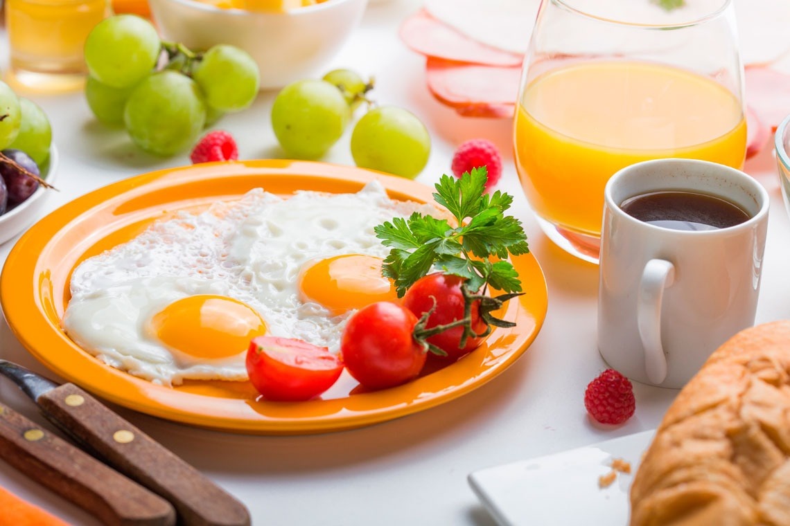 un plato de huevos fritos con tomates y un vaso de jugo de naranja