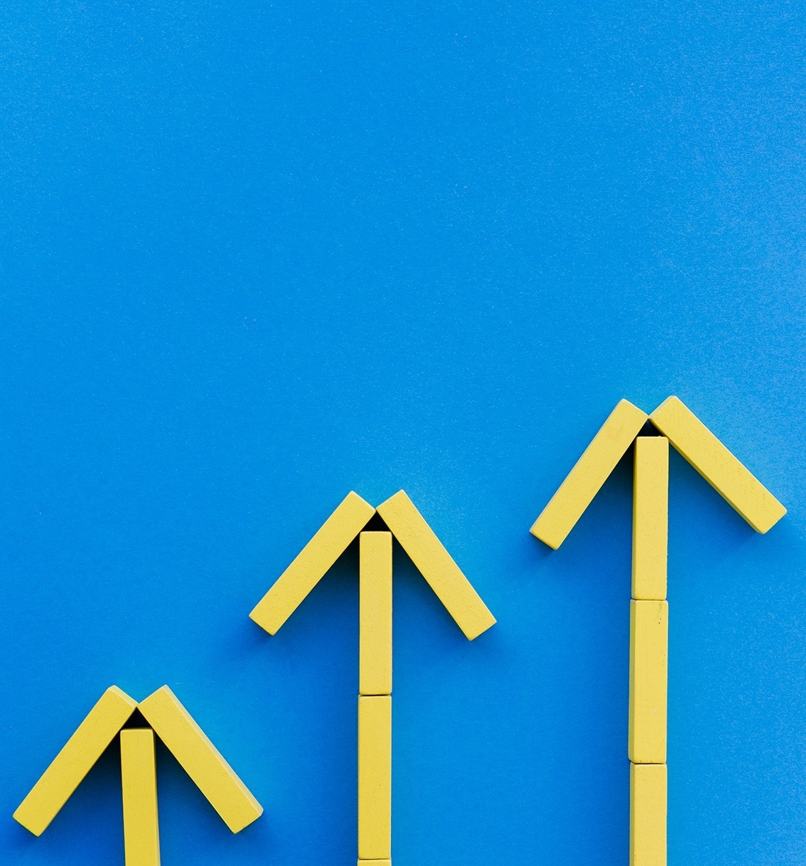 tres flechas amarillas apuntan hacia arriba sobre un fondo azul