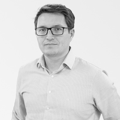 a man wearing glasses and a white shirt is standing in a black and white photo .