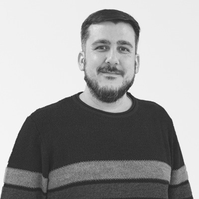 a black and white photo of a man with a beard wearing a striped sweater