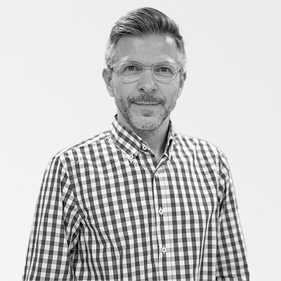 a man with glasses and a beard is wearing a plaid shirt .