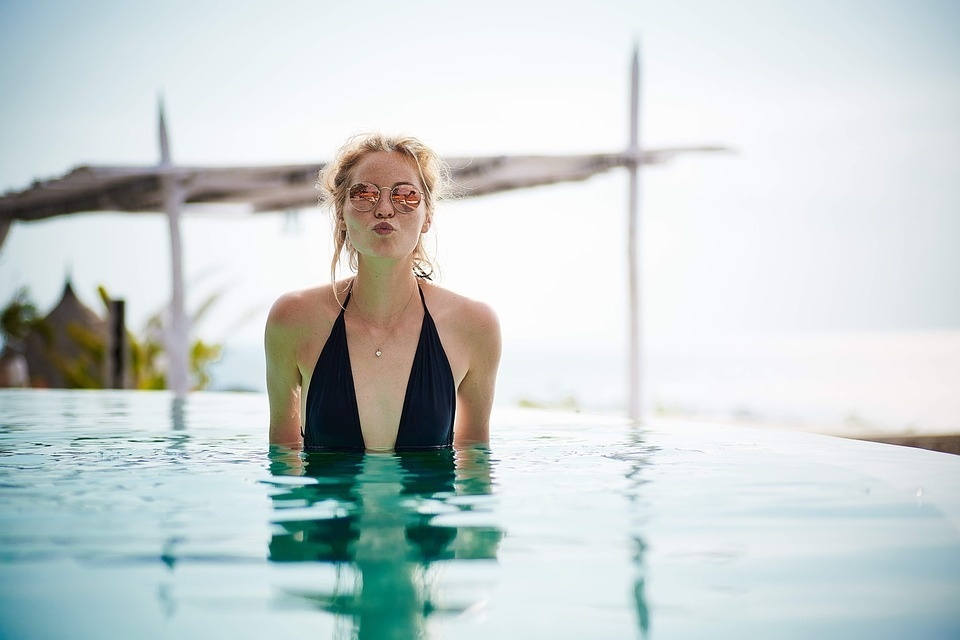 a woman wearing sunglasses is sticking her tongue out in a swimming pool