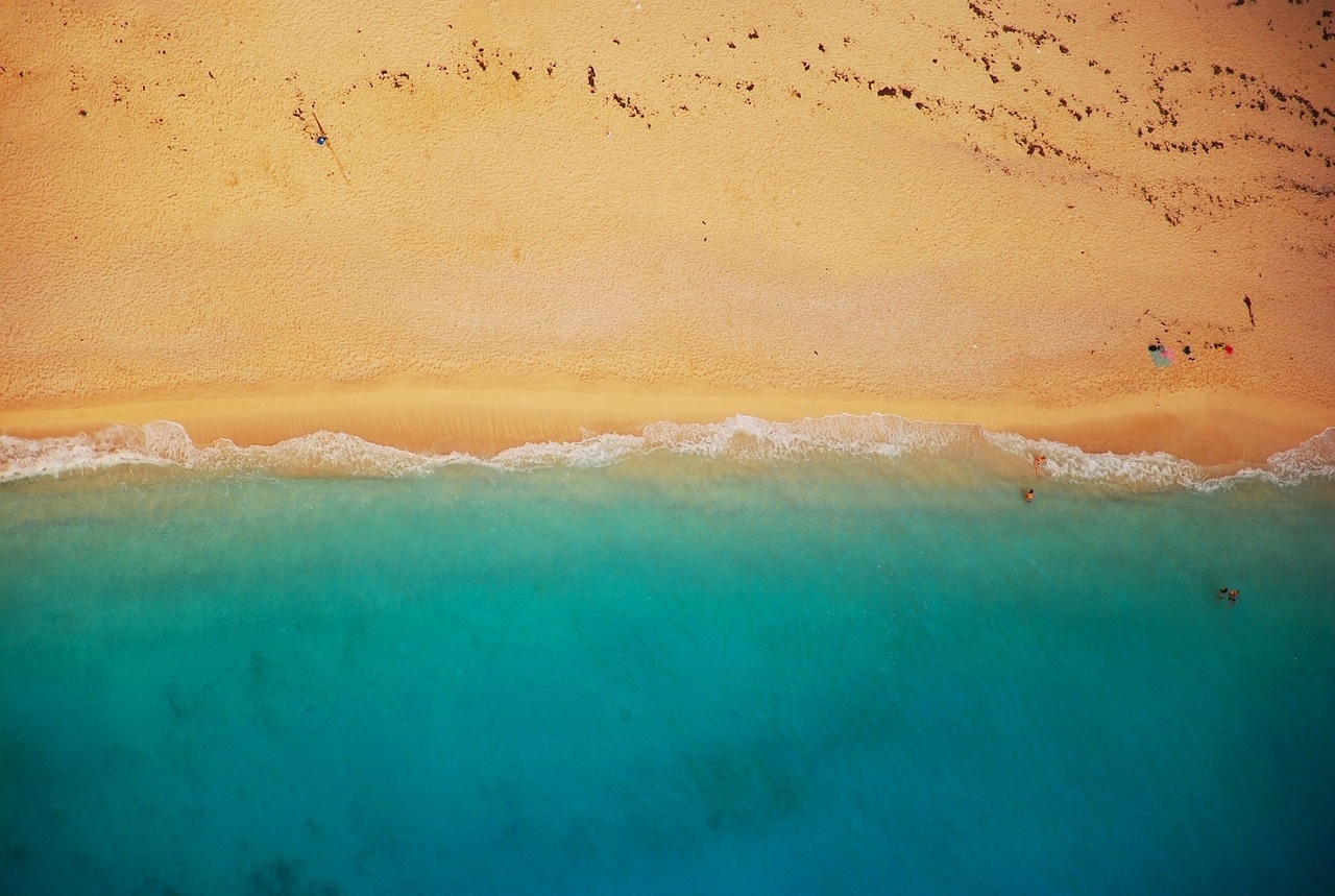 an aerial view of a sandy beach with blue water