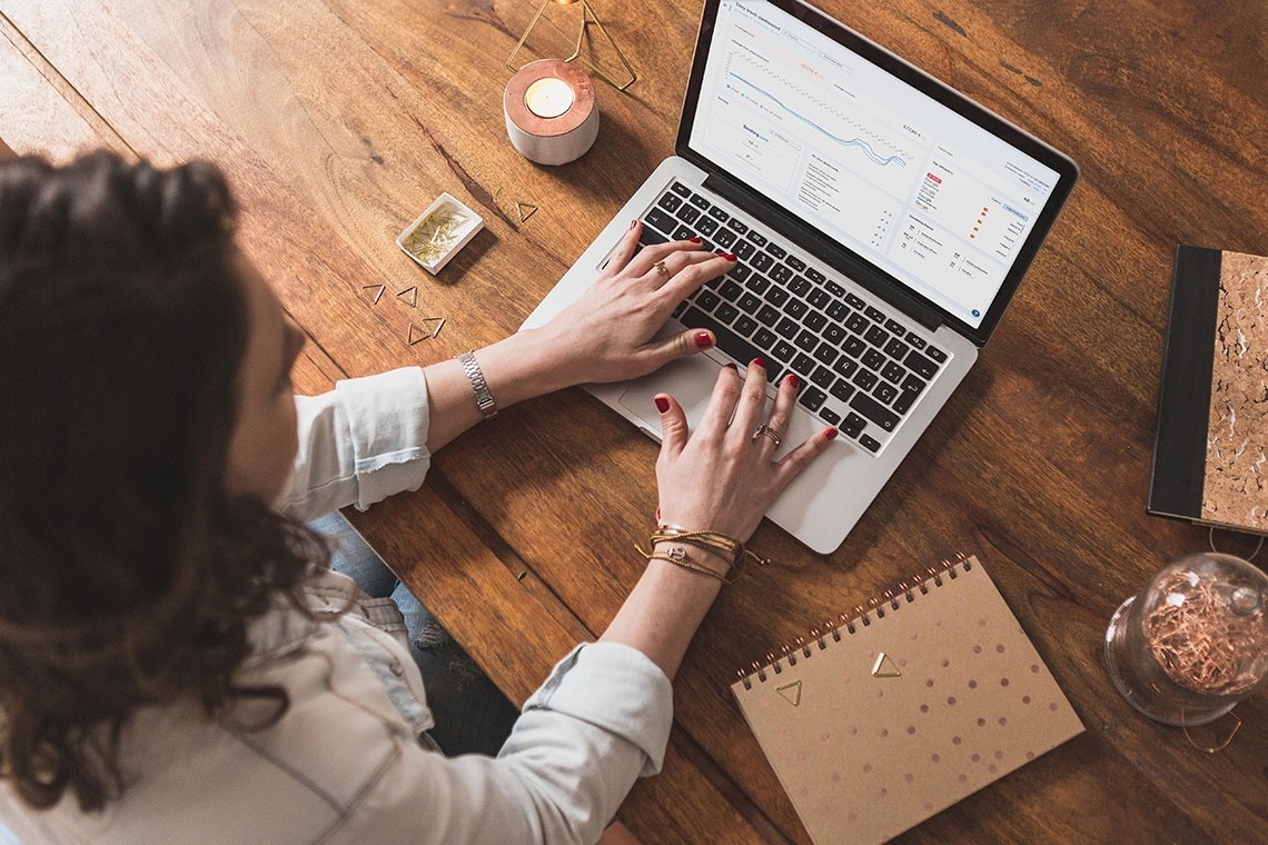 una mujer sonríe mientras usa una computadora portátil con la página web oficial en la pantalla