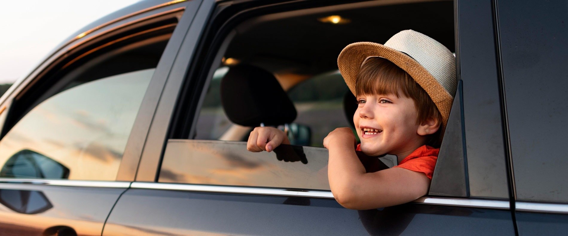 un niño con un sombrero mira por la ventana de un coche .