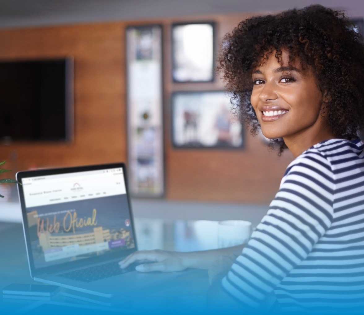 una mujer sonríe mientras usa una computadora portátil con la página web oficial en la pantalla