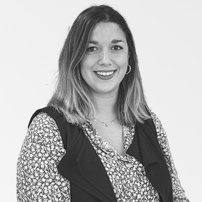 a woman wearing a floral shirt and a black vest is smiling in a black and white photo .