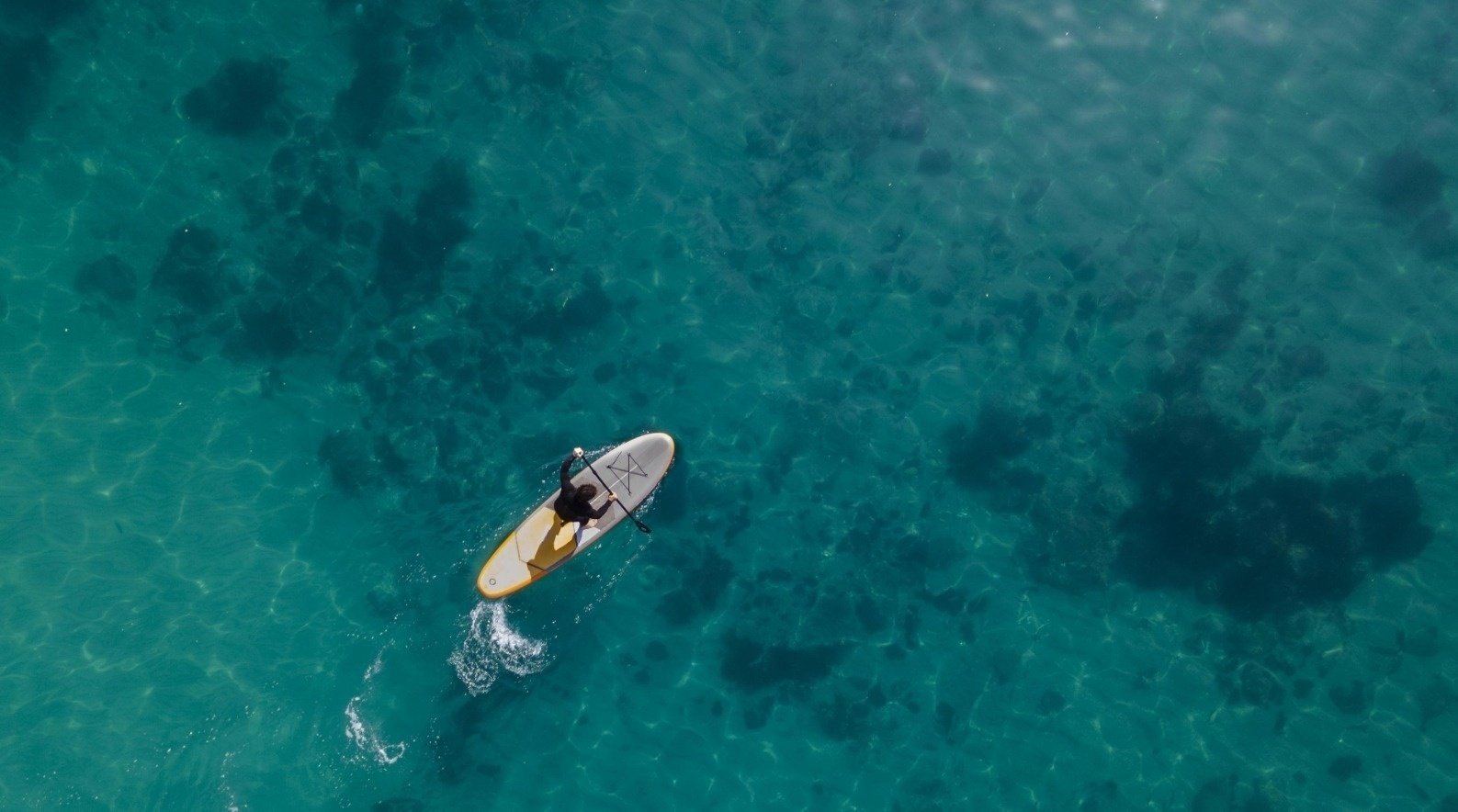 una vista aérea de una persona en una tabla de surf en el océano