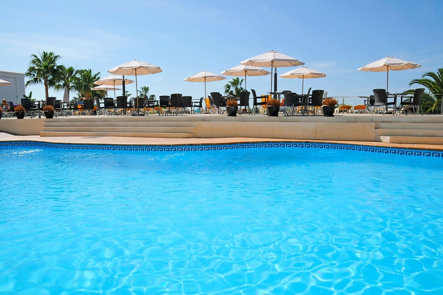 a swimming pool with tables and umbrellas around it