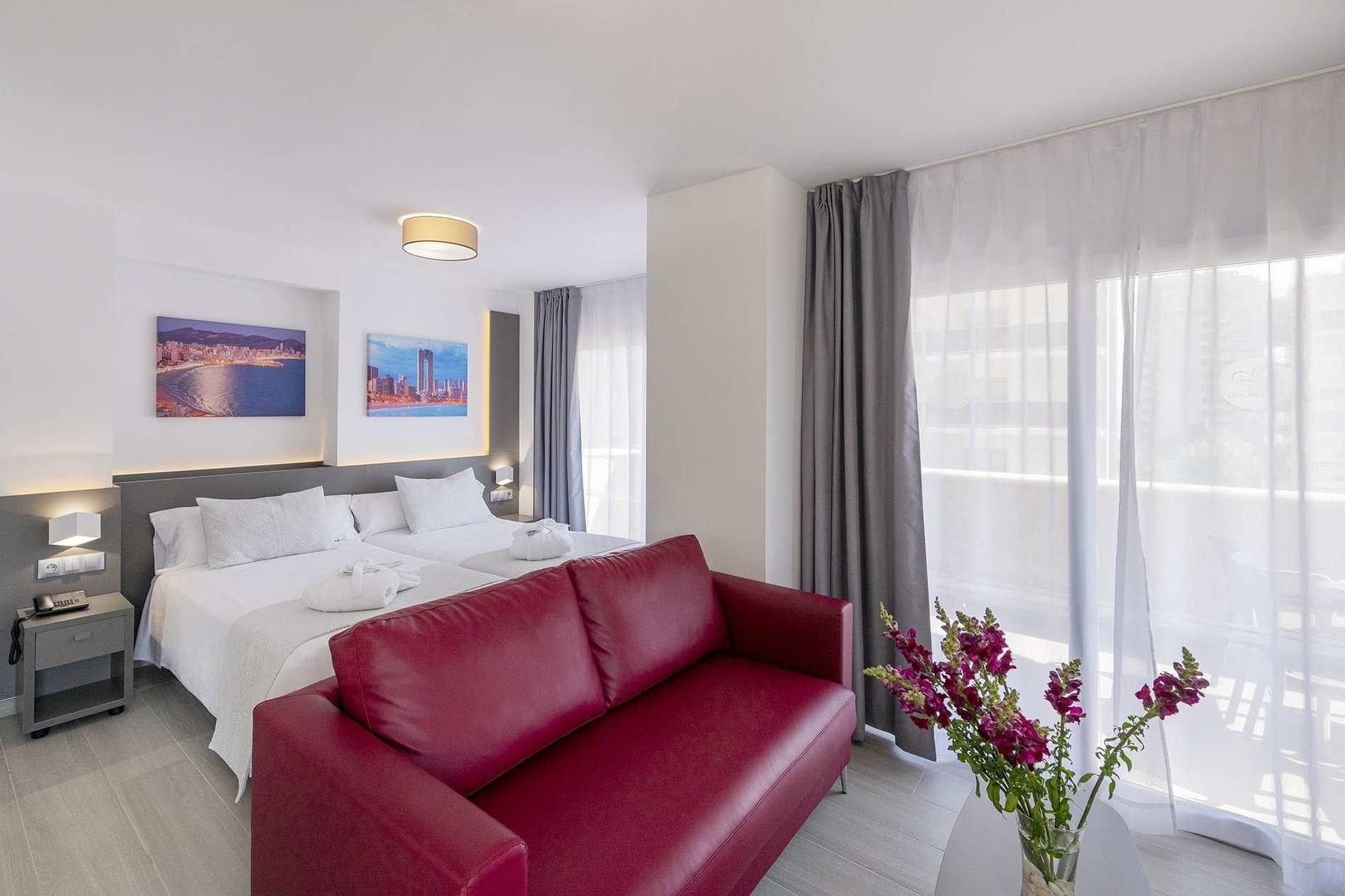 una habitación con dos camas y un sofá rojo