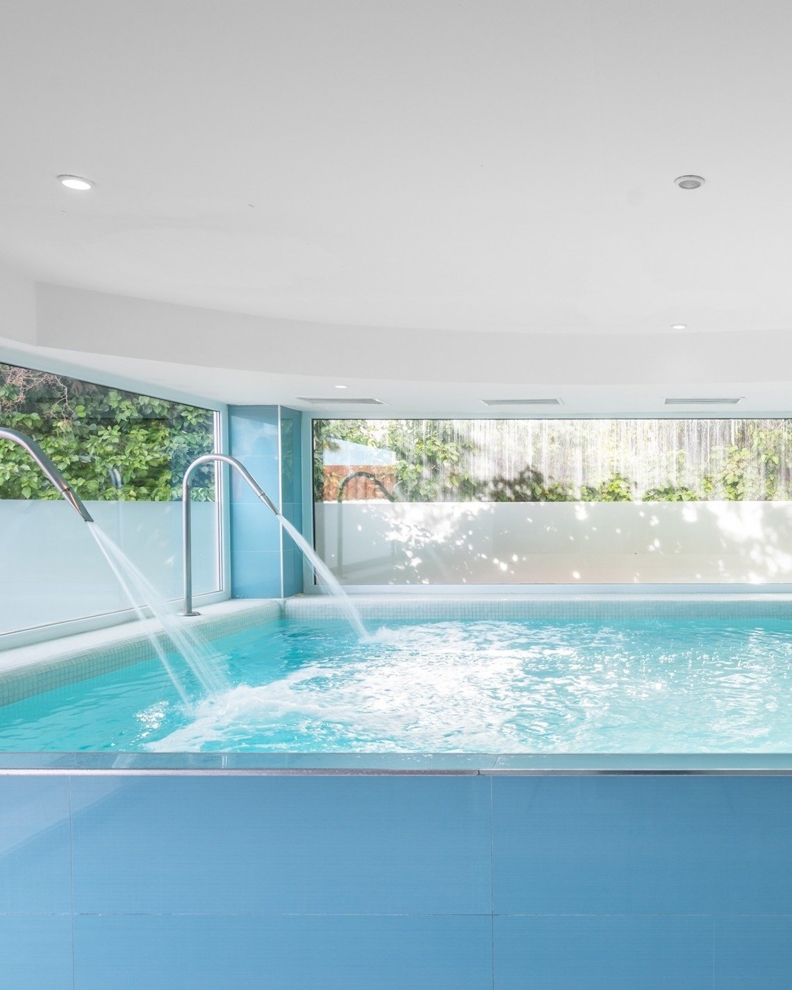 una piscina azul y blanca con un jacuzzi en el fondo