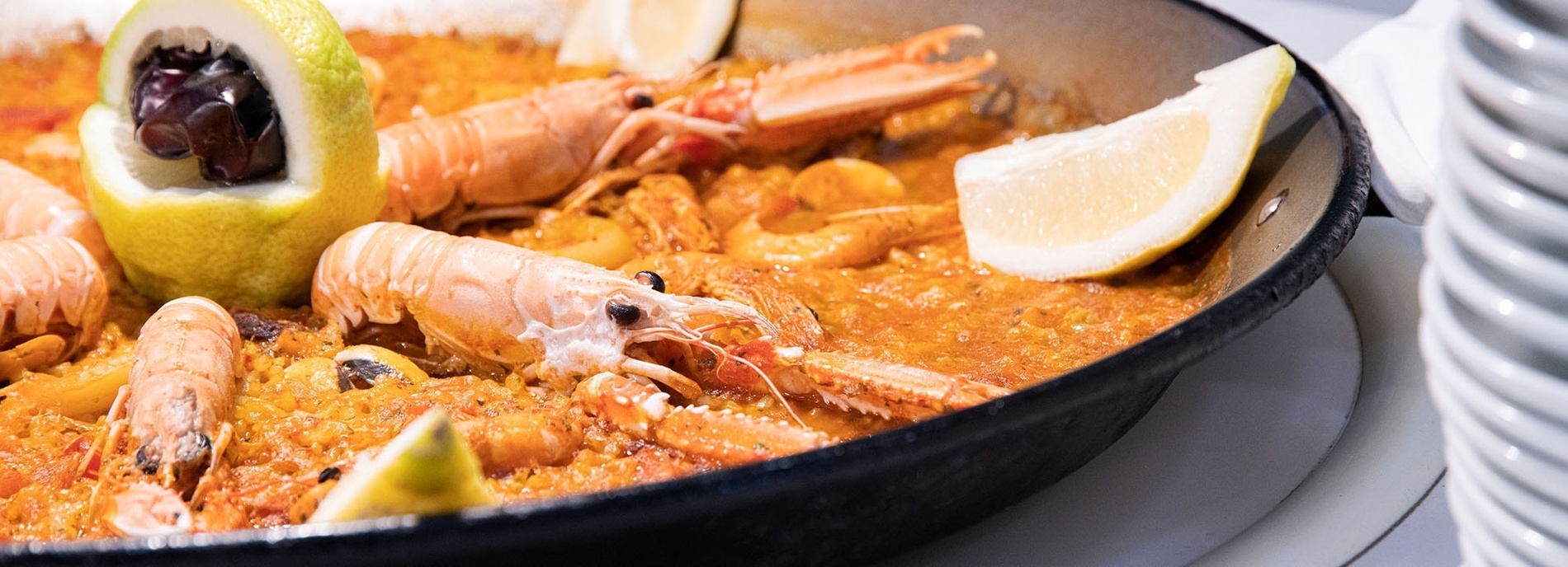 een pan paella met garnalen en citroenschijfjes